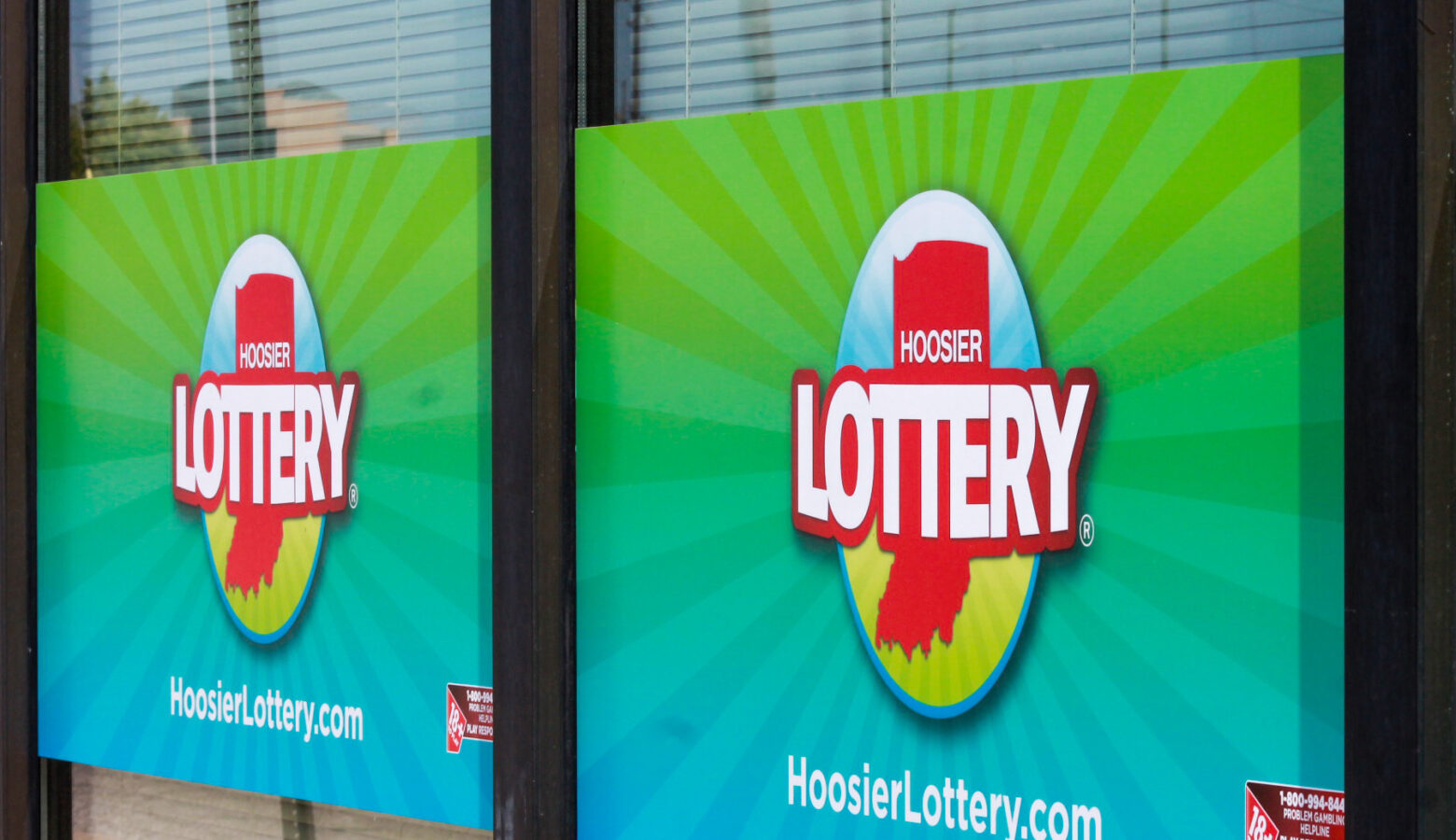 Two signs hanging in a window show the logo for the Hoosier Lottery.