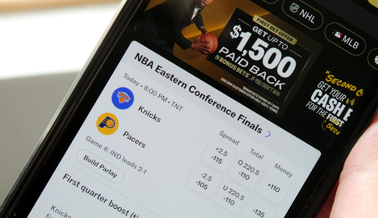 A phone screen shows a sports betting site.