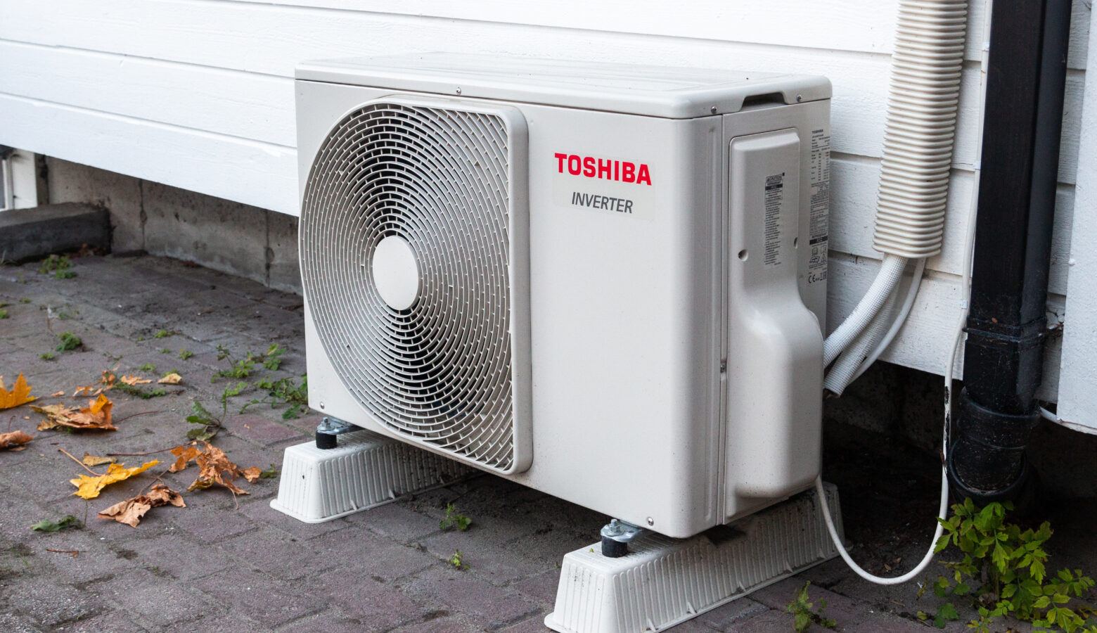 A Toshiba inverter heat pump sits outside of a building. It's a rectangular box with a fan on its outside.