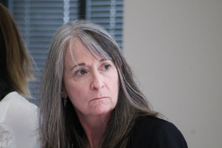 Holly Wimsatt, director of the Bureau of Disabilities Services within FSSA, listens to advocate questions at a Division of Disability and Rehabilitative Service Advisory Council meeting. She is a white woman with bangs and long hair that is mostly grey, but brown in some sections. She wears a black blazer.