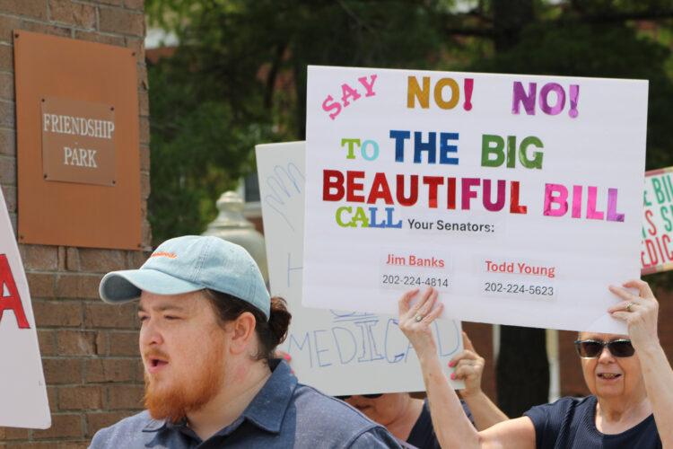 People marching and holding signs, one sign reads "Say No! No! To the Big Beautiful Bill. Call your Senators: Jim Banks 202-222-4814, Todd Young 202-224-5623."