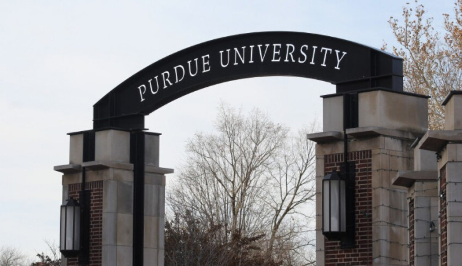 A photo on the Purdue campus of a gateway with a small arch on which is written Purdue University.