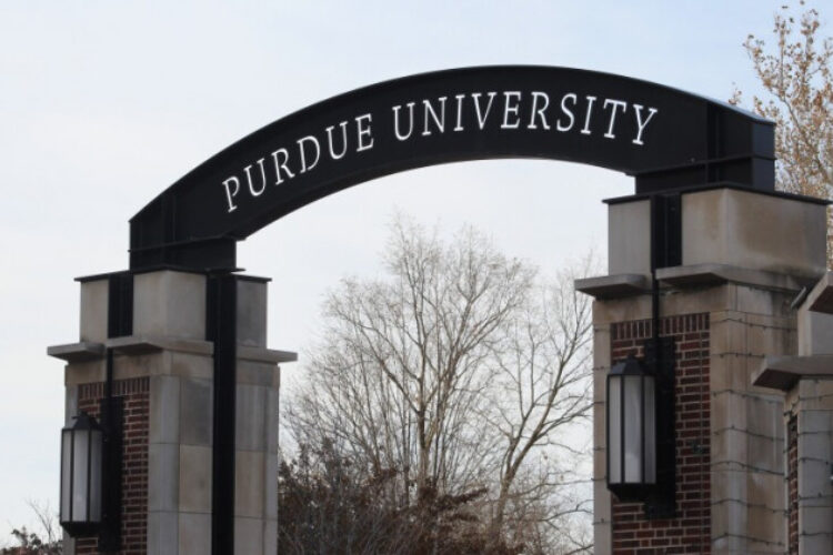 A photo on the Purdue campus of a gateway with a small arch on which is written Purdue University.