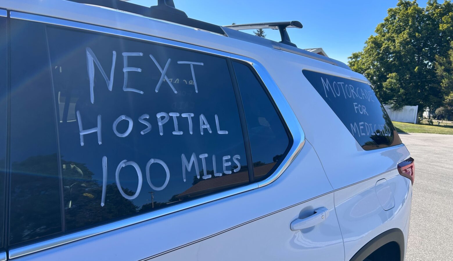 The side of a white car with the words "Next Hospital 100 Miles" written on it.