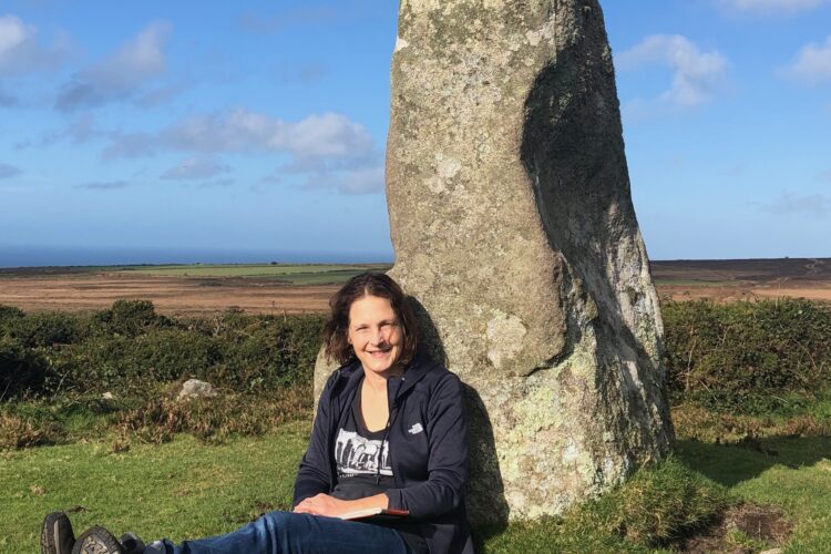 Fiona Robertson sitting next to a stone outside.