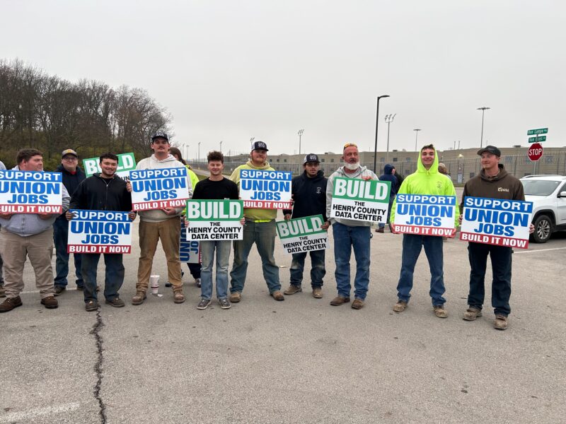 A line of people standing shoulder to shoulder holding signs