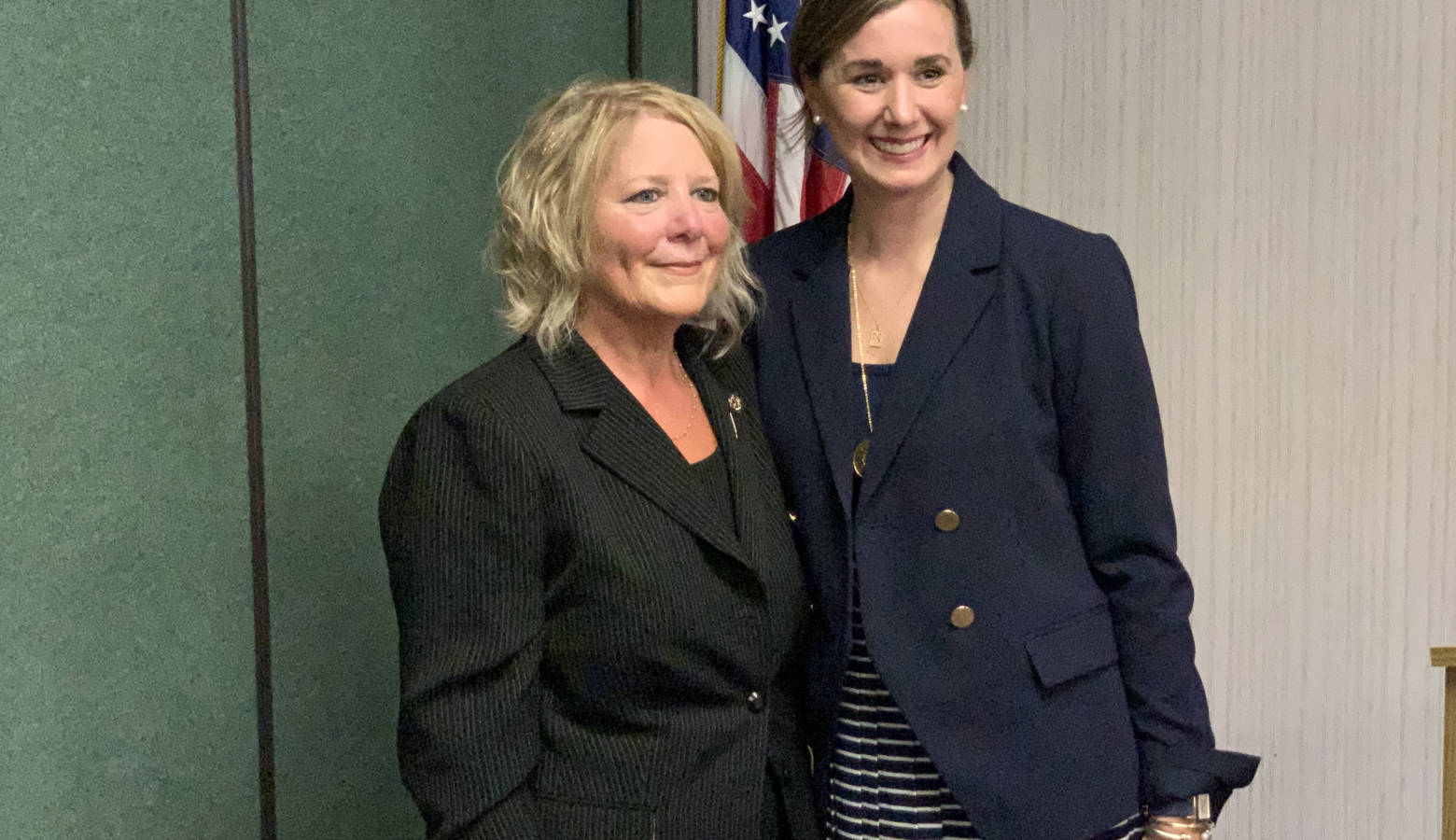 Dollyne Sherman is a white woman with blond hair. She wears a dark suit.