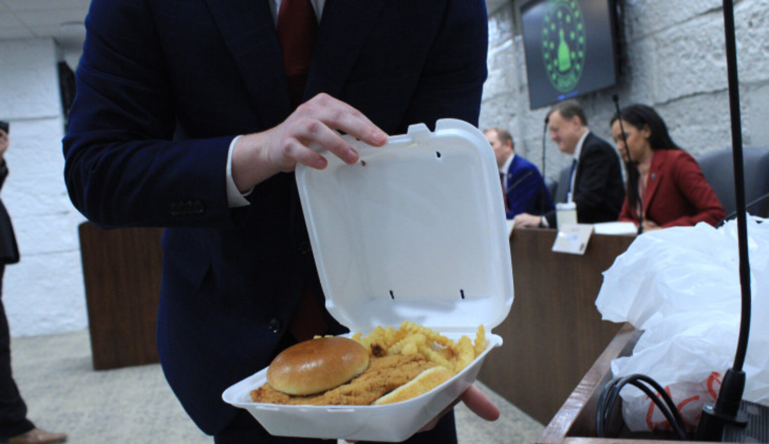 A pork tenderloin sandwich is displayed in a styrofoam dinner box.