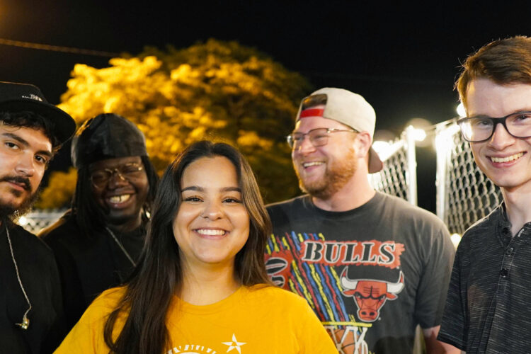 Five people stand together and smile at the camera.