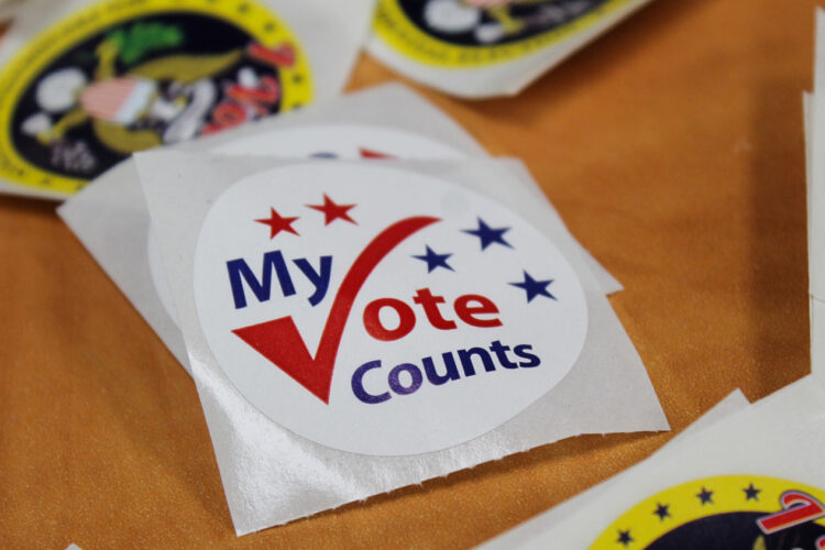 A sticker on a table reads My Vote Counts