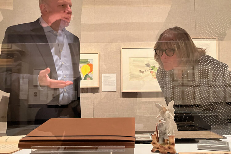 A man and a woman are seen behind a glass display, looking at the objects within the display.