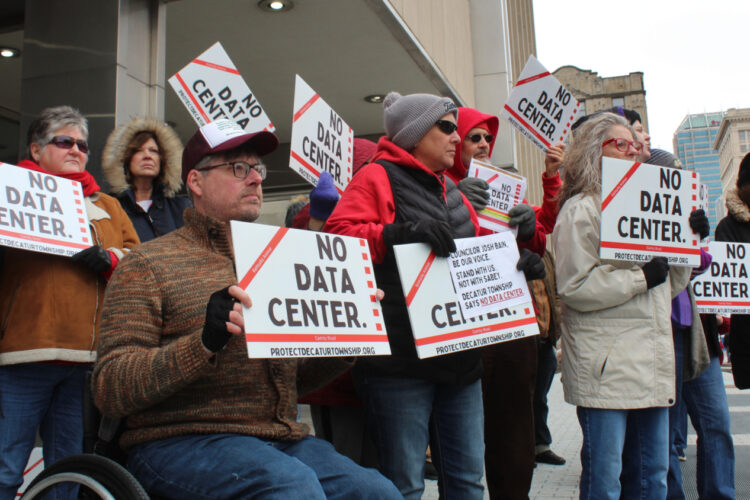 Residents of Decatur Township hold signs and chant outside the Indianapolis City-County Building Wednesday, March 18, 2026. The group was protesting the proposed data center on the southwest side of Marion County ahead of the Metropolitan Development Commission's vote.