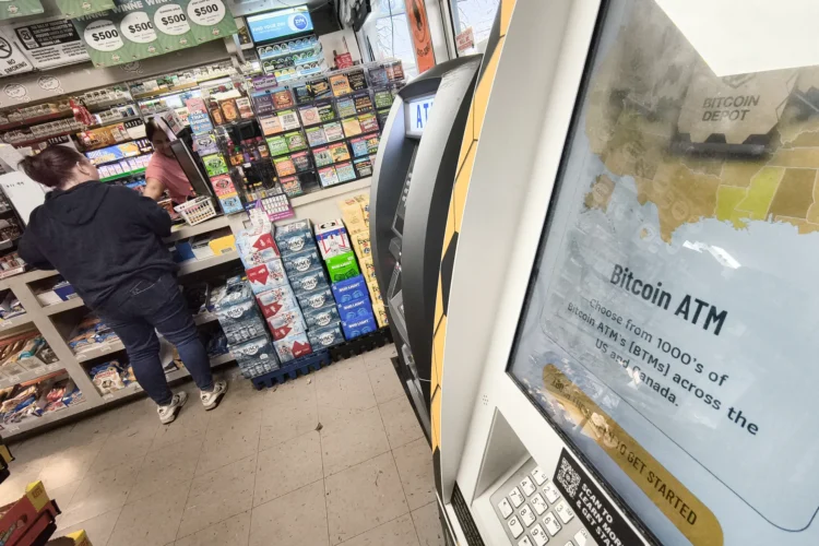 An interior view of the checkout area of a convenience store with a Bitcoin ATM in the right side of the frame in the foreground.