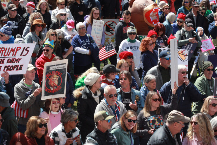 A packed crowd of protesters stands outside of the Indiana statehouse -- many holding signs against the Trump Administration.