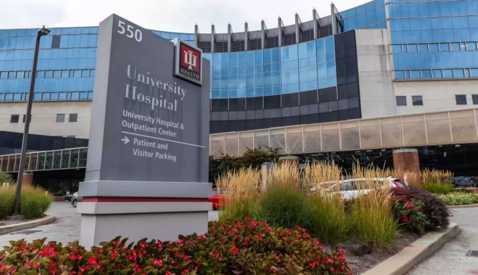 A concrete and glass building stands behind a sign that reads "University Hospital IU Health"