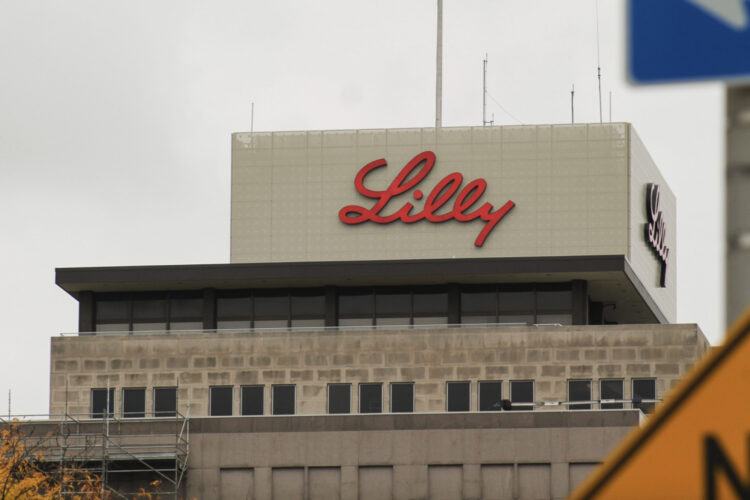 Eli Lilly's headquarters is a large building made of gray stone and glass. At its top, the word Lilly is written in red script.