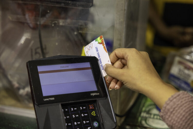 A person swipes a benefits card through a card-reader at a grocery store.