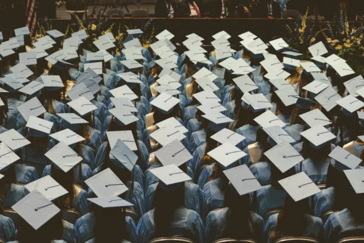 A view from above a class of graduates at a commencement ceremony showing a sea of mortar board caps.