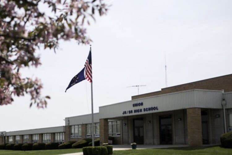 Union Junior / Senior High is a one-story brick building with front columns. An American flag on a pole flies outside.