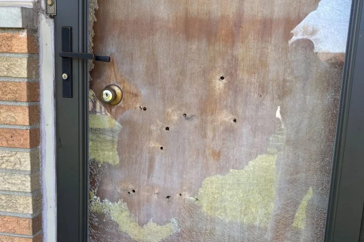 A wooden door with several small bullet holes scattered throughout it