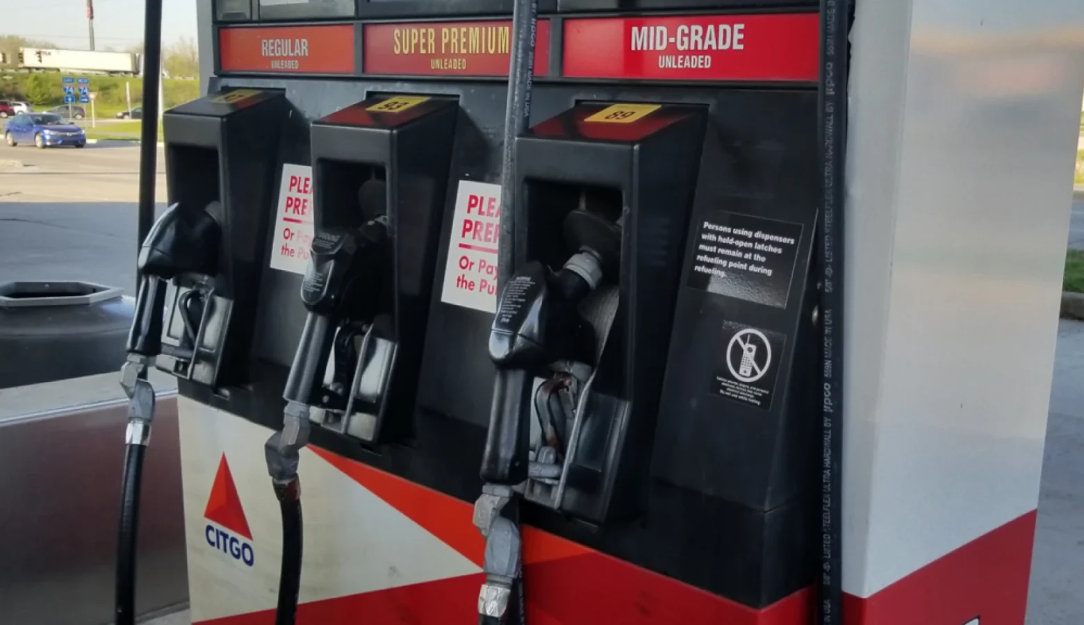 A close-up of a gas pump with three gas nozzles waiting to be used.