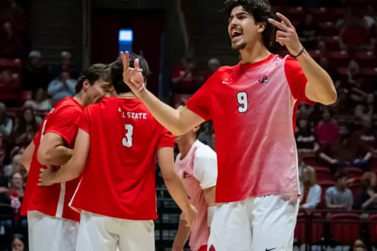 Ball State men's volleyball players celebrate a point. They are dressed in red jerseys and white pants.