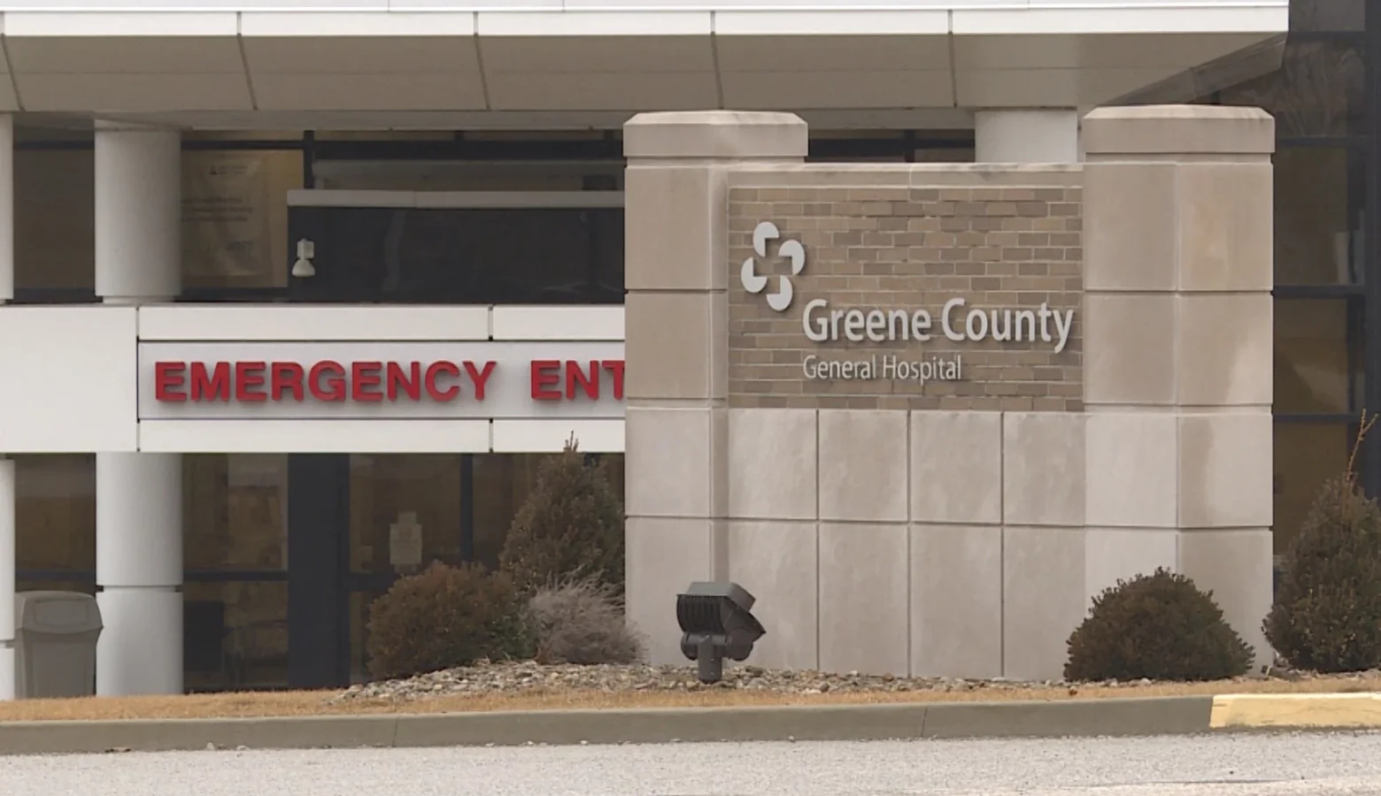 An exterior photo of the front of the Greene County General Hospital showing a stone sign with the hospital's name and logo. To the left of the sign is the Emergency Entrance marked in large, all-capital, red lettering.