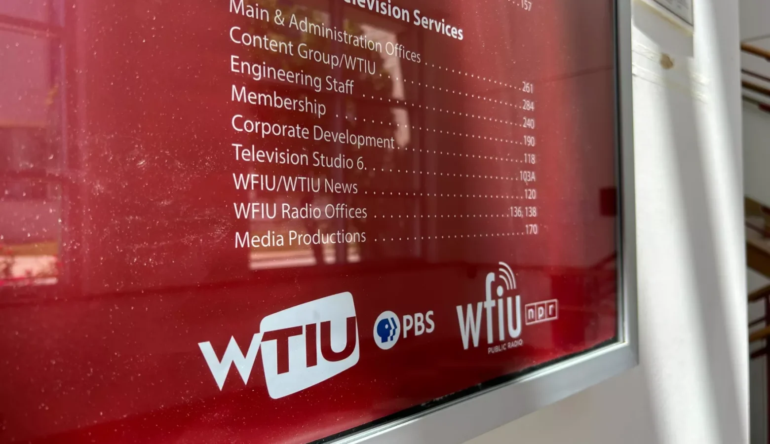 An interior photo of an office directory sign for WTIU and WFIU at IU Bloomington. The sign has white type on a crimson background.
