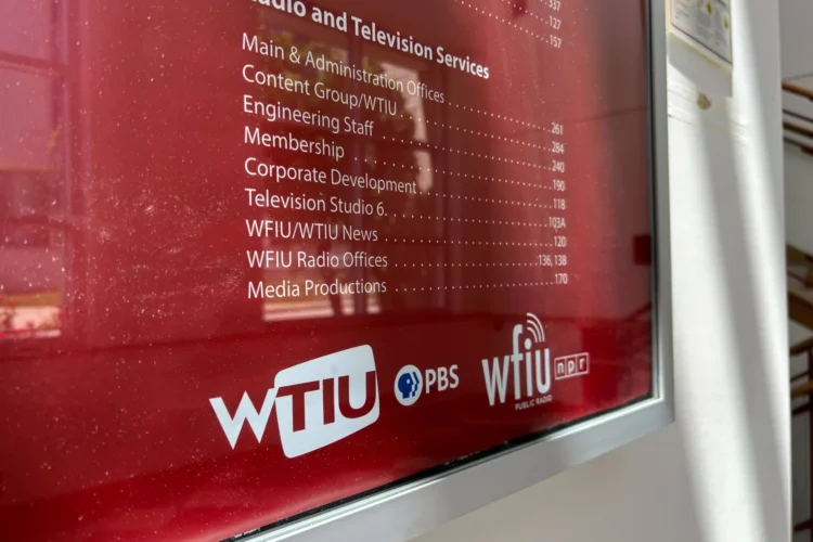 An interior photo of an office directory sign for WTIU and WFIU at IU Bloomington. The sign has white type on a crimson background.
