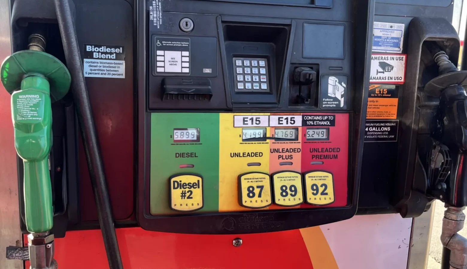 An Indianapolis gas pump shows ethanol allotments in each fuel grade. The pump shows, from left to right, #2 Diesel in a green-painted part of the pump with a diesel dispenser with a green plastic head. Further to the right, in order, we see Unleaded 87 gas highlighted in yellow with 87 octane, then orange-labeled 89 octane Unleaded Plus (both unleaded and unleaded plus show E15 on a label in their respective sections. Finally, in red, we see Unleaded Premium with a label that says "Up to 10% Ethanol." A black-headed gasoline dispenser is positioned to the right of the gasoline choices.