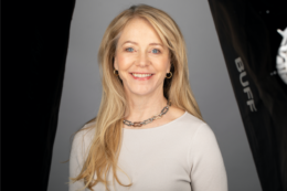 Elizabeth "Liza" Yntema stands smiling for a portrait. She has long blonde hair and is wearing a long sleeve top and a necklace.