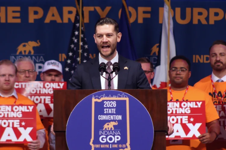 Max Engling speaking to delegates Saturday, June 20, 2026 at the Republican Party convention in Fort Wayne. He is standing behind a podium with a GOP State Convention logo within a blue circle on the front of the podium. He is flanked by supporters holding signs saying "Citizen Only Voting -- Vote Max"