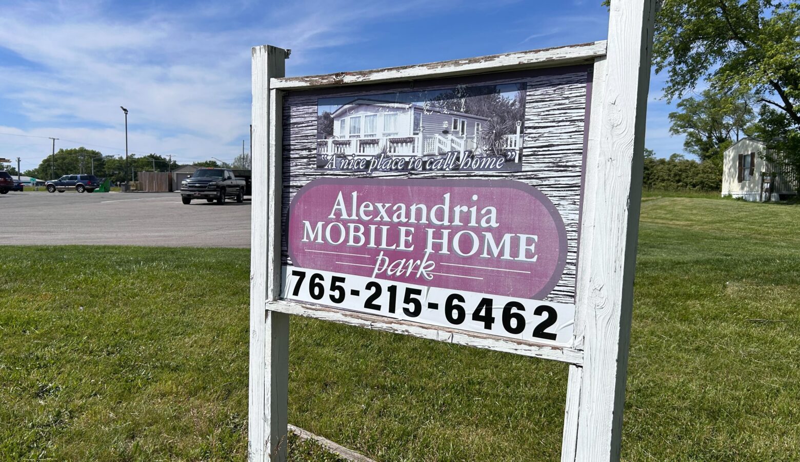 An old wooden sign with a faded image and the words "Alexandria Mobile Home Park"