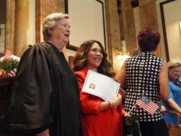 An Indiana judge poses for a photo with a woman holding up a certificate showing she's now a naturalized US citizen.