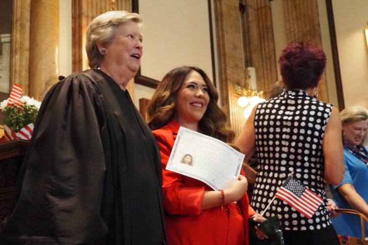 An Indiana judge poses for a photo with a woman holding up a certificate showing she's now a naturalized US citizen.