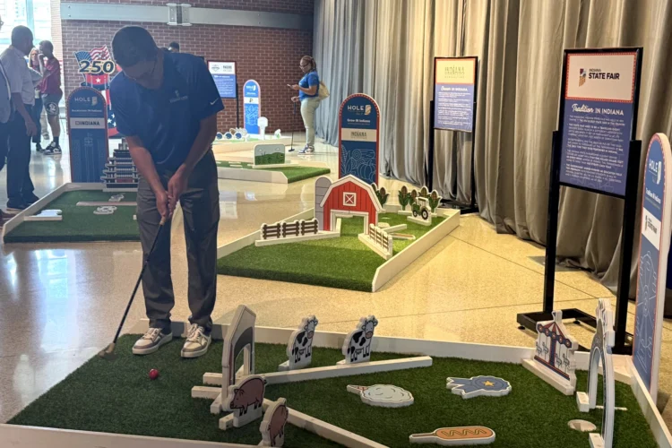 A person stands at a small mini-golf display, about to shoot a ball towards the hole.
