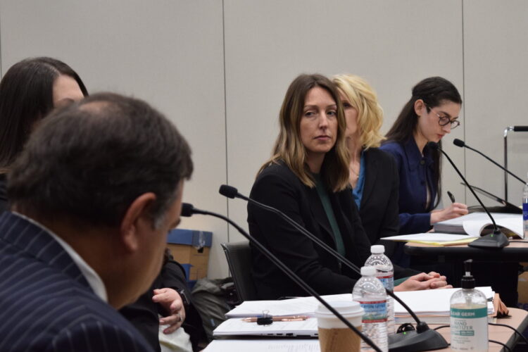 Dr. Caitlin Bernard waits for a question in a courtroom setting, seated with her lawyers behind a table with microphones.
