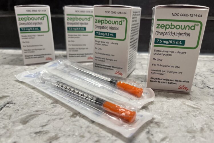 Four boxes of Zepbound GLP-1 medication vials sit in boxes next two two single-use needles in plastic.