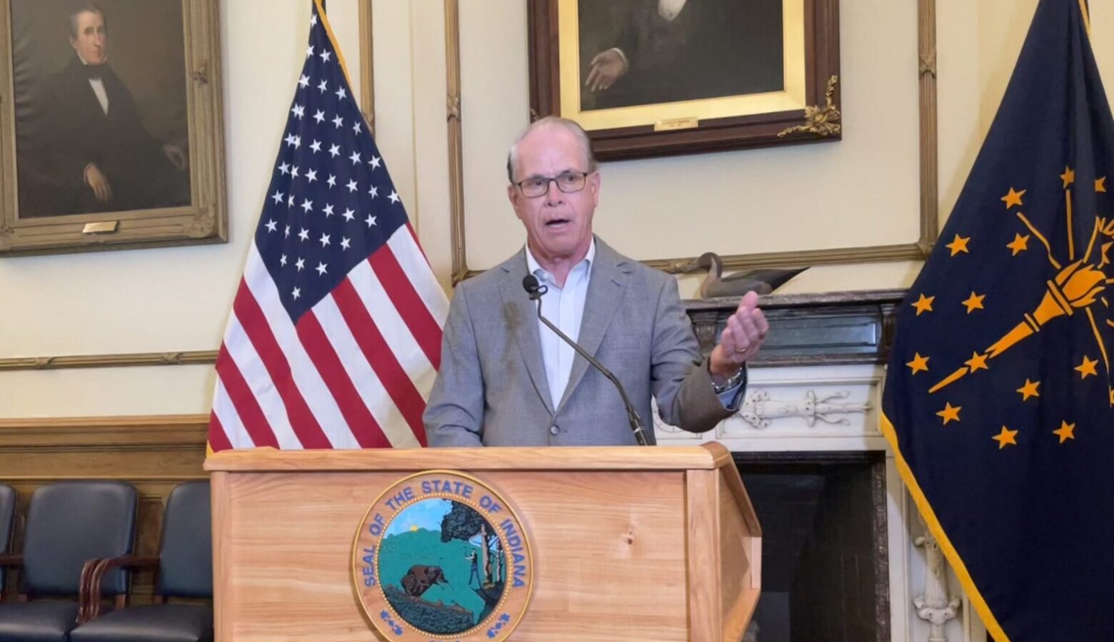 Governor Mike Braun speaks from a podium in his office, surrounded by the American and Indiana flags.