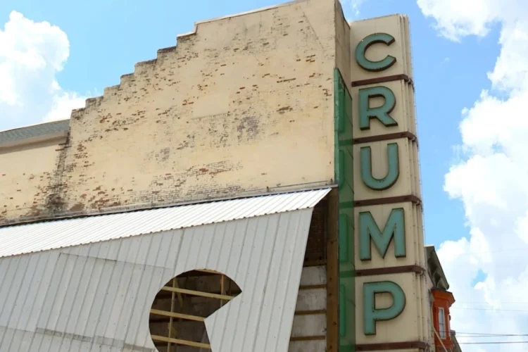 The Crump Theater in Columbus, Indiana is one of 49 recipients of this year's annual READI grants. An exterior photo looking skyward sows the CRUMP sign positioned vertically and brick walls with peeling paint. A fair-weather sky is above the theater.