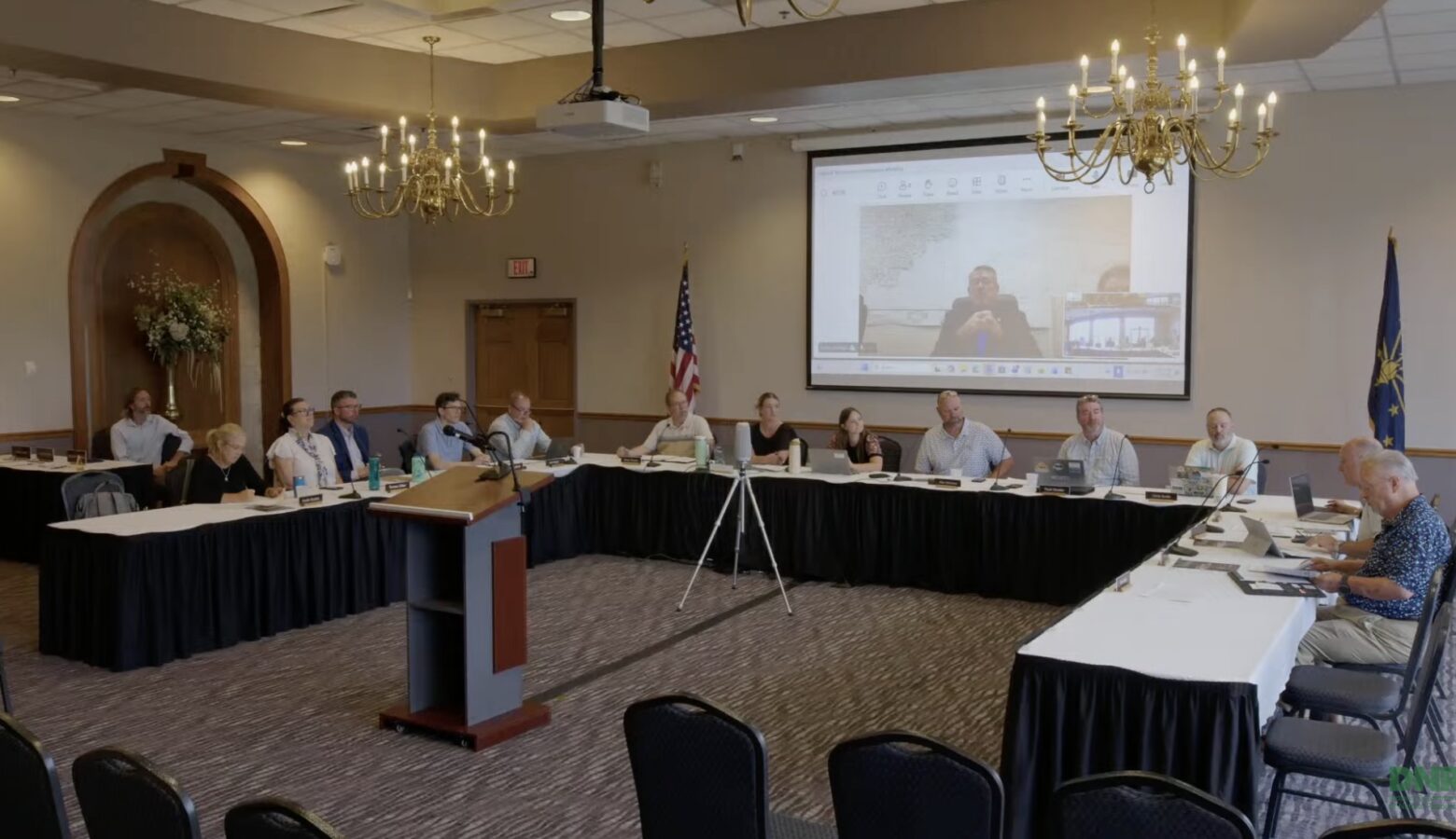 A video screenshot shows a meeting of the Natural Resources Commission, whose members are sitting around a u-shaped table formation in a conference room.