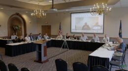 A video screenshot shows a meeting of the Natural Resources Commission, whose members are sitting around a u-shaped table formation in a conference room.