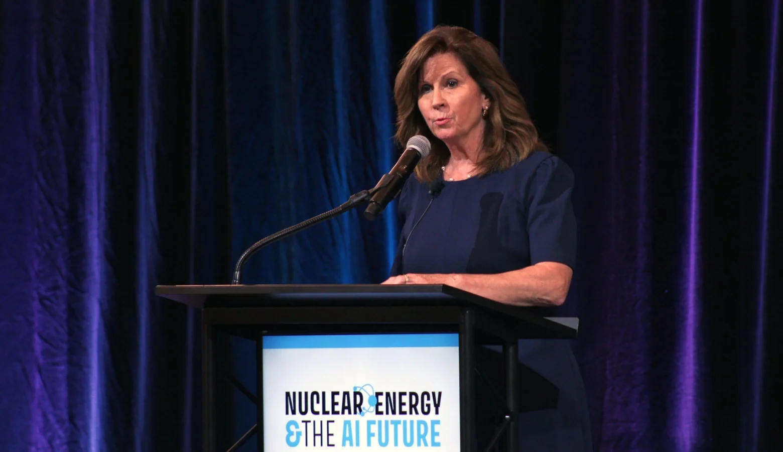 Energy Secretary Suzanne Jaworowski speaking on a stage at a podium, with a sign that reads Nuclear Energy and the AI Future.