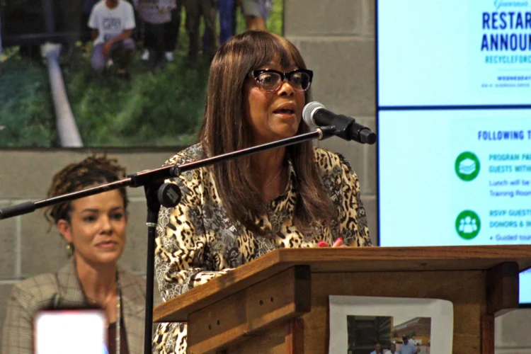 Jannette Keesling at Recycleforce stands at a podium and speaks about a new multi-million dollar grant for the organization.