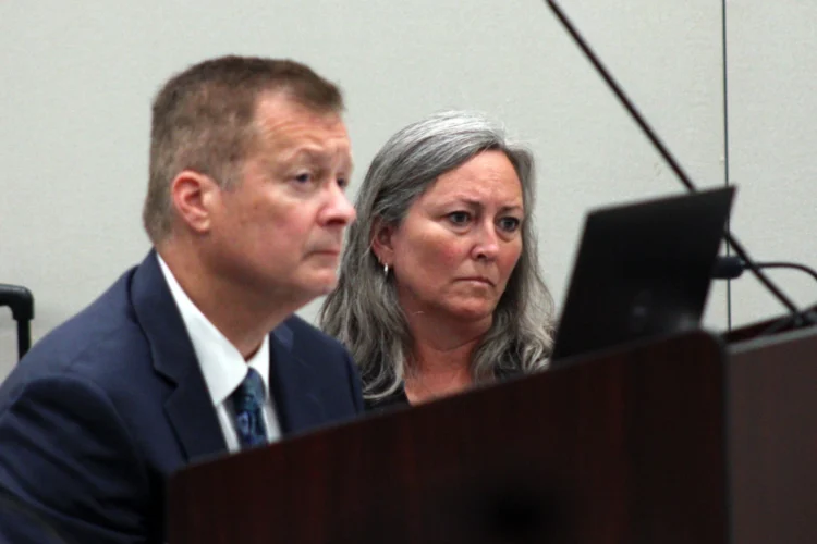 A man and woman sit in a room during a meeting, listening to election officials consider her state Senate race.