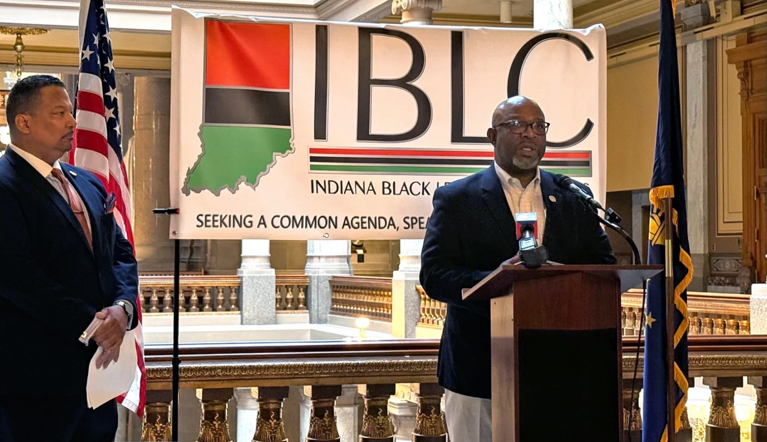 Sen. Greg Taylor and Rep. Earl Harris speak in front of a banner that reads Indiana Black Legislative Caucus at a Statehouse press conference.