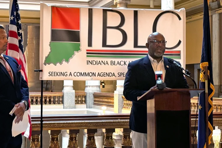 Sen. Greg Taylor and Rep. Earl Harris speak in front of a banner that reads Indiana Black Legislative Caucus at a Statehouse press conference.
