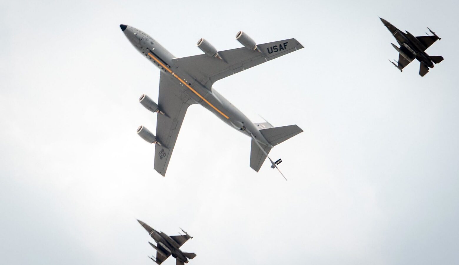 Three U.S. Air Force planes, as seen from below, fly across the sky.