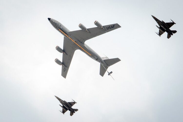 Three U.S. Air Force planes, as seen from below, fly across the sky.