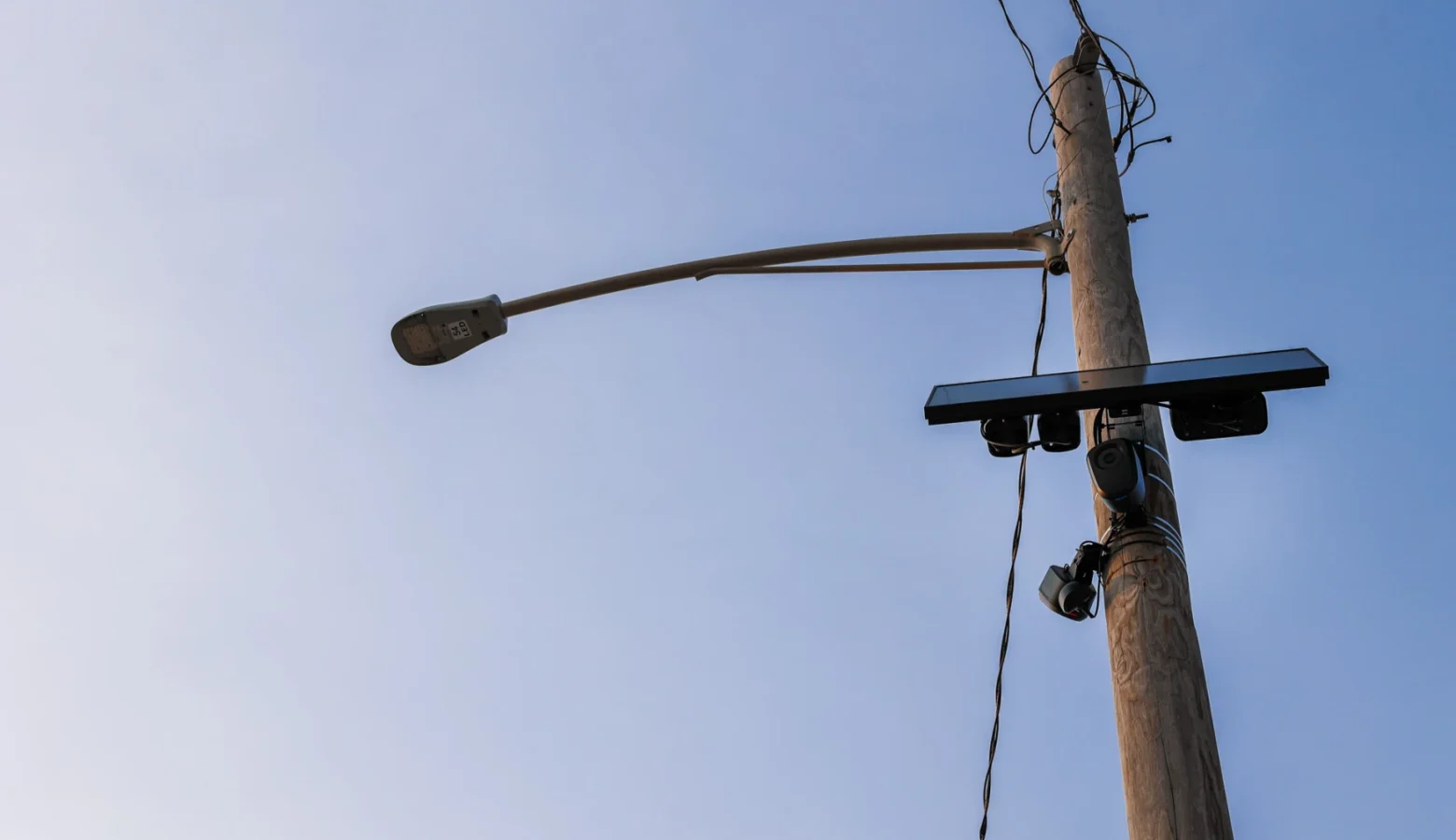 Flock's license plate-reading cameras have spread around the country. This one sits near Promenade Park in downtown Fort Wayne. City council is evaluating whether to continue their contract with the company. The camera is affixed to a utility pole. The photo is looking upward toward a blue sky.